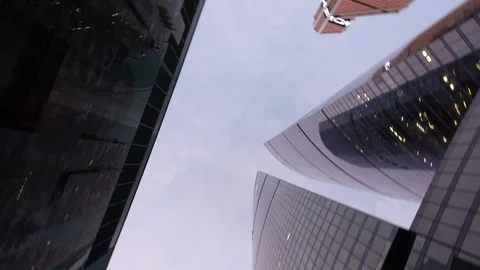 Low angle shot of camera rotating in front of modern, office tower buildings Video stock 104826015