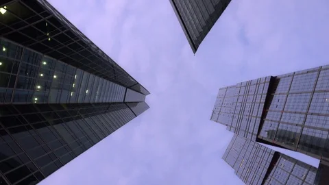 Low angle shot of camera rotating in front of modern, skyscrapers. Daytime Stock Footage 104828339