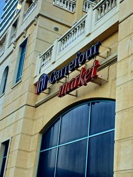 A low-angle shot captures the "Carrefour Market" sign on a light-colored Stock-Fotos