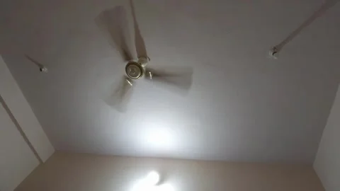 A low-angle shot captures a fan blurring under harsh fluorescent lights, symboli Vidéo 343784318