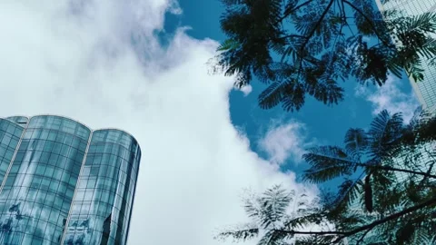 A low-angle shot captures a modern glass-clad building with cylindrical shape in Stock Footage 338165568