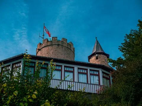 Low angle shot of a castle with a window front and an old tower with a flag.. 스톡 사진