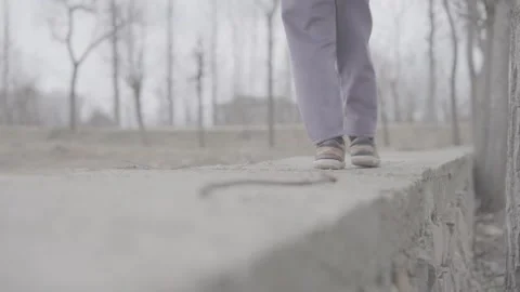 Low angle shot of child walking along a concrete wall in slow motion Stock-Footage 327597162