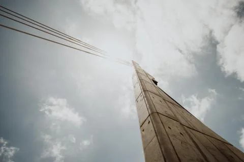 Low angle shot of a concrete column with cables against a bright cloudy sky Stock Photos
