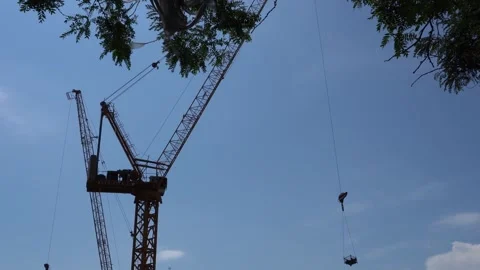 Low angle shot of construction crane lifting a load against a clear blue sky 動画素材 335353426