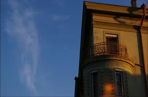 Low angle shot of corner of ornamental building with round balcony under blue sk Stock Photos