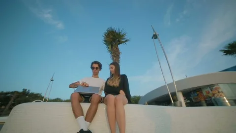 Low angle shot couple in love sits on white concrete parapet Stock Footage 102815517