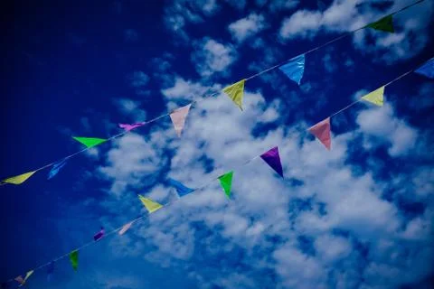 A low angle shot of different color flags on a rope with a blue cloudy sky in Foto stock