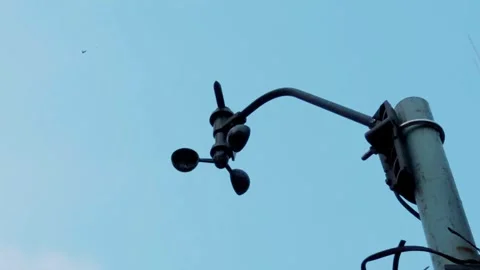 Low-angle shot of a digital cup anemometer spinning against a clear blue sky. Stock Footage 337768256