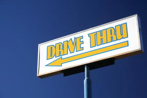 A low angle shot of a drive-thru sign at a restaurant with an arrow pointer u Stock Photos