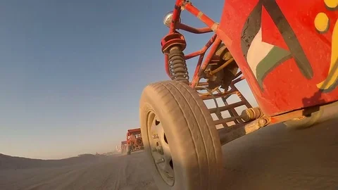 Low angle shot of dune buggies driving in a line through the desert Vídeo Stock 85058520