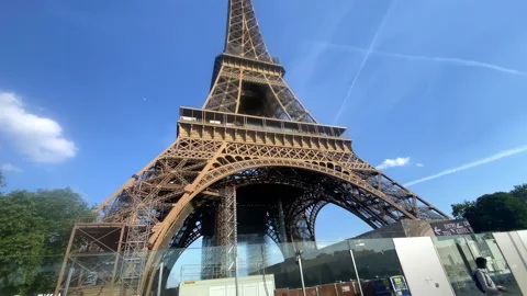 Low angle shot of the Eiffel Tower in Paris, France with tourists passing by Stock Footage 197361849