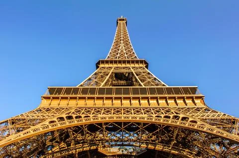 Low angle shot of the Eiffel tower on the background of the bright blue sky Stock Photos