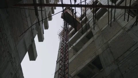 Low angle shot of elevator suspended between buildings during construction in Stock Footage 307189665