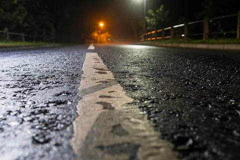 A low angle shot of an empty road on a misty night with street lights Stock Photos