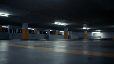 Low angle shot of empty underground parking, dimly lit with ceiling lamps. Vídeos de archivo 286256581