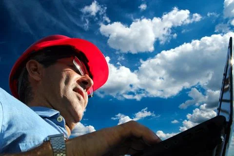 Low Angle Shot Of A Engineer At Work With Laptop Computer Against Blue Sky Stock Photos