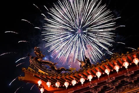 Low angle shot of exploding fireworks over a Chinese building roof Stock Photos