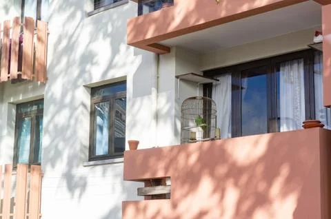 Low angle shot of the facade of a building with a parrot cage on the balcony Foto stock