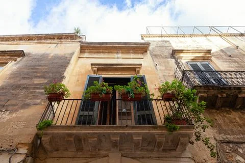 Low angle shot of a facade old building with balcony with pot plats against blue Fotos de archivo