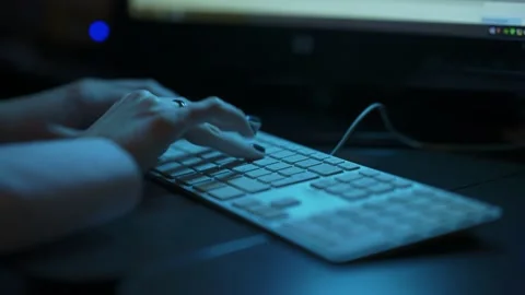 Low angle shot of female hands typing on a keyboard in a backlit dark office. Stock Footage 198924293