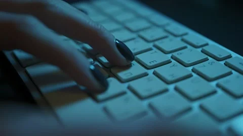 Low angle shot of female hands typing on a keyboard in a backlit dark office. Stock Footage 198924357