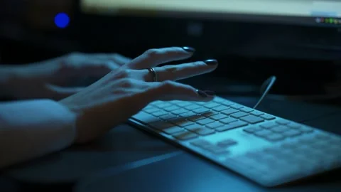 Low angle shot of female hands typing on a keyboard in a backlit dark office. Stock Footage 199104340