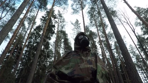 Low-angle shot of gasmasked man in forest Stock Footage 146012582