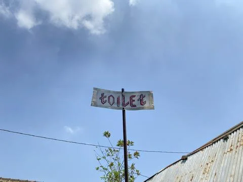 Low angle shot of a hand-painted TOILET sign mounted on a pole. Stock Photos