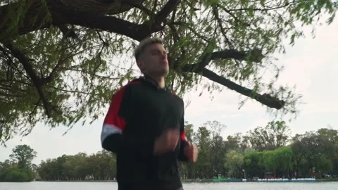 Low angle shot of a handsome man running at park beside lake Stock-Footage 140551329
