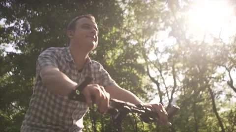 Low angle shot of happy calm middle age man in plaid shirt riding slow urban bik Stock Footage 132672479