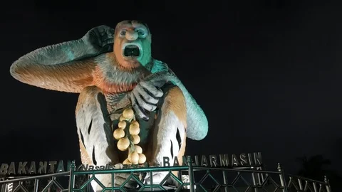 Low angle shot of iconic Proboscis monkey statue with colorful lights at night Stock Footage 105550046
