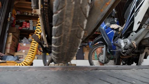 Low angle shot of Indonesian man repairing motorcycles in a local garage, Bali Stock Footage 140294250