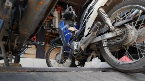 Low angle shot of Indonesian man repairing motorcycles in a local garage, Bali Stock Footage 140294371