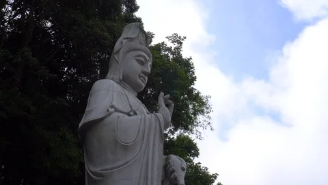 Low angle shot of large Buddha statue with trees and sky in the background Stock Footage 91123003