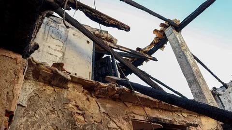 Low-angle shot looking up at a destroyed roof structure with charred wooden.. Stock Photos