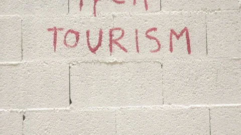 Low-Angle Shot Looking Up at 'Fuck Tourism' Graffiti Wall Stock Footage 340286173