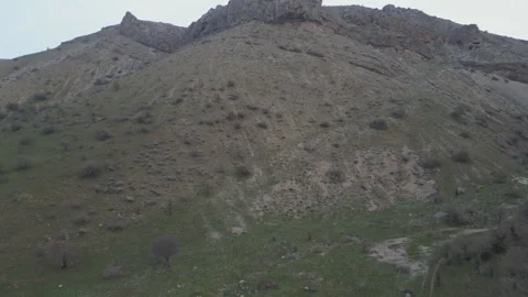 A low-angle shot looking up a steep, rocky hill with a craggy, dark summit. Stock Footage 331164571