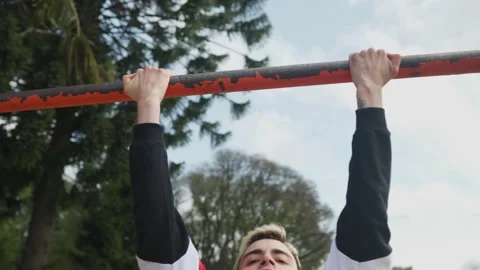 Low angle shot of a man doing pull-ups on a bar at park. Orbit Stock-Footage 140589474