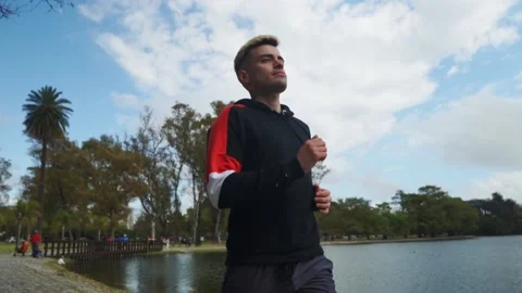 Low angle shot of a man running at park beside lake. Slow motion Stock-Footage 140590563