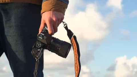 Low angle shot of man walking outside holding a camera leash Stock Footage 99104715