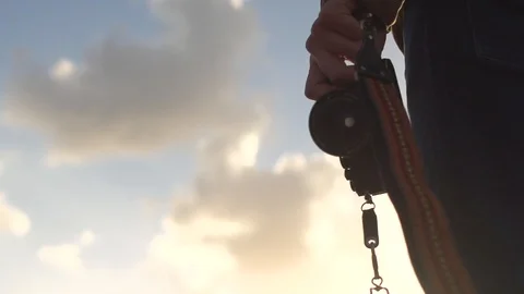 Low angle shot of man walking outside holding a camera leash Vídeo Stock 99105391