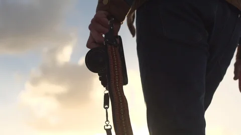 Low angle shot of man walking outside holding a camera leash Stock Footage 99167282