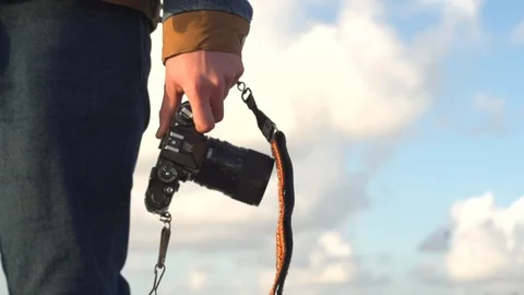 Low angle shot of man walking outside holding a camera leash Stock Footage 99168581
