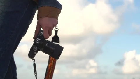 Low angle shot of man walking outside holding a camera leash Stock Footage 99168658