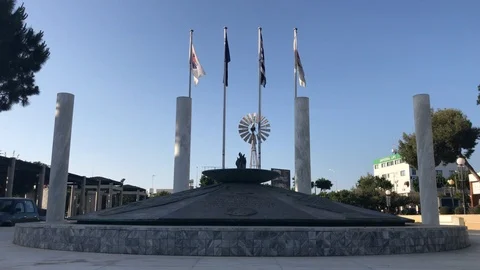Low Angle Shot of a monument vs waving flags and windmill at the background Stock Footage 91568650