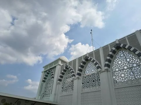 A low-angle shot of a mosque's white exterior with intricate geometric screens Stock Photos