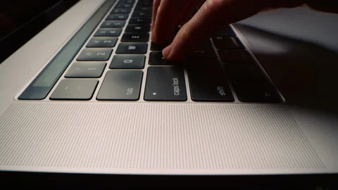 Low angle shot moving across laptop computer keyboard as woman types quickly 8K Stock Footage 122561138
