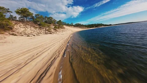 Low-angle shot moving across golden sand meeting ocean edge Stock Footage 340905083