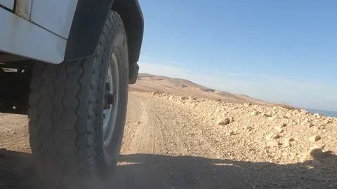 Low-angle shot of an offroad car running over a dirt track and picking up dust Stock Footage 175687149